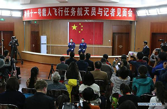 Chinese astronauts Jing Haipeng (L) and Chen Dong meet the media at a press conference at the Jiuquan Satellite Launch Center in northwest China, Oct. 16, 2016